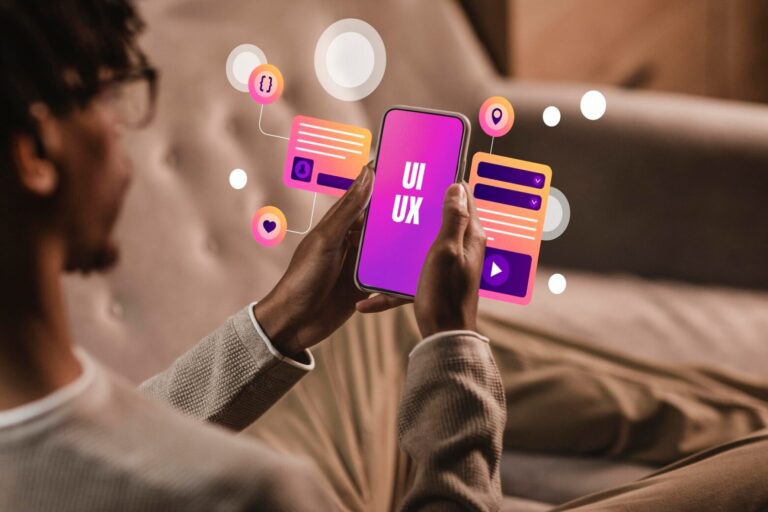Image of Person holding a smartphone with UI/UX design elements floating around, representing app development
